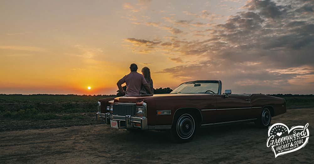 A couple sitting on a car to watch the sunset